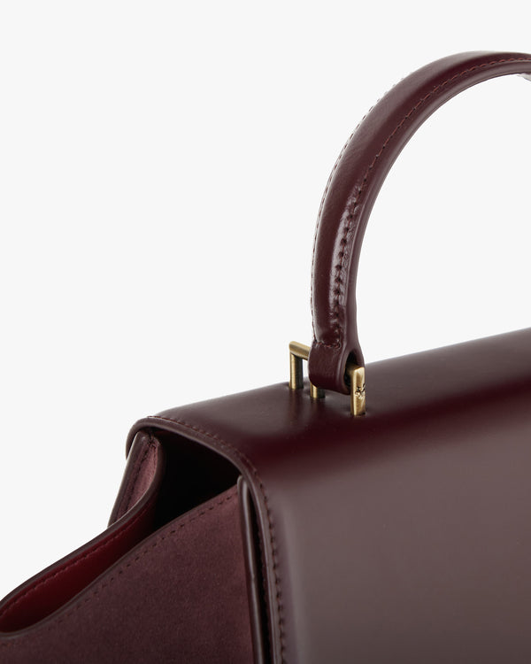 ALEXIA bag in Mahogany, close-up of the wrapped handle and gold-tone hardware on the flap