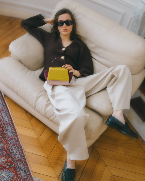 ALEXIA NANO bag in Colourblock Vesper held by top handle, carried in hand, seated on a sofa