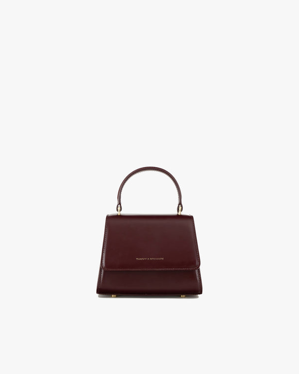 ALEXIA NANO bag in Mahogany, front view, flap closed, top handle raised, on white background