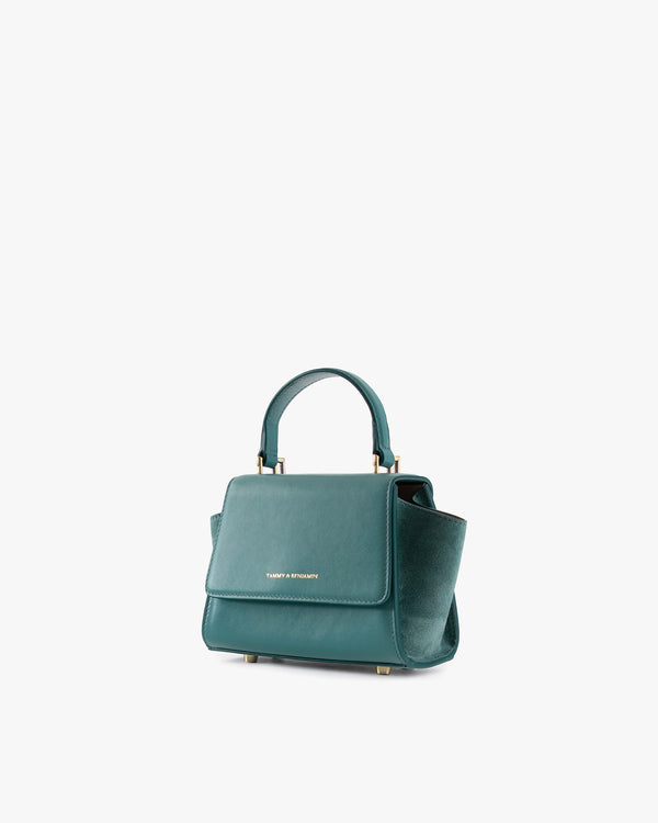 ALEXIA NANO bag in turquoise, three-quarter view, short handle, closed flap, placed on the ground