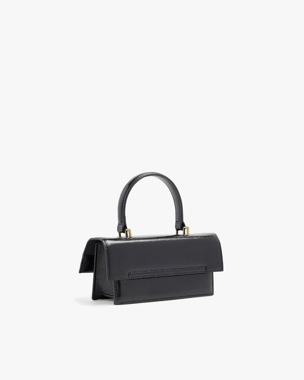 THEA MINI bag in black naplak, rear three-quarter view, standing, showing flap and handle