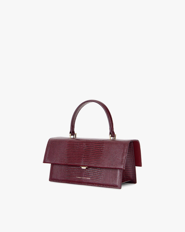 THEA bag in burgundy embossed lizard, three-quarter view, flap closed, top handle raised