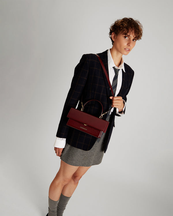 THEA bag in bordeaux naplak leather, worn crossbody by the top handle, front view