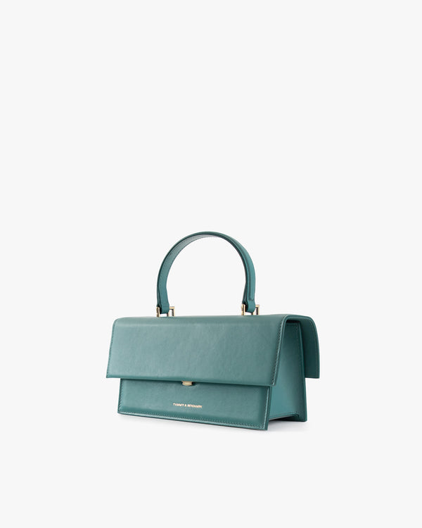 THEA bag in turquoise, three-quarter view, flap closed, top handle raised