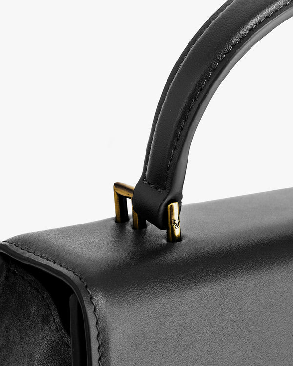 ALEXIA bag in black, close-up of the padded handle and gold-tone metal fittings on the flap