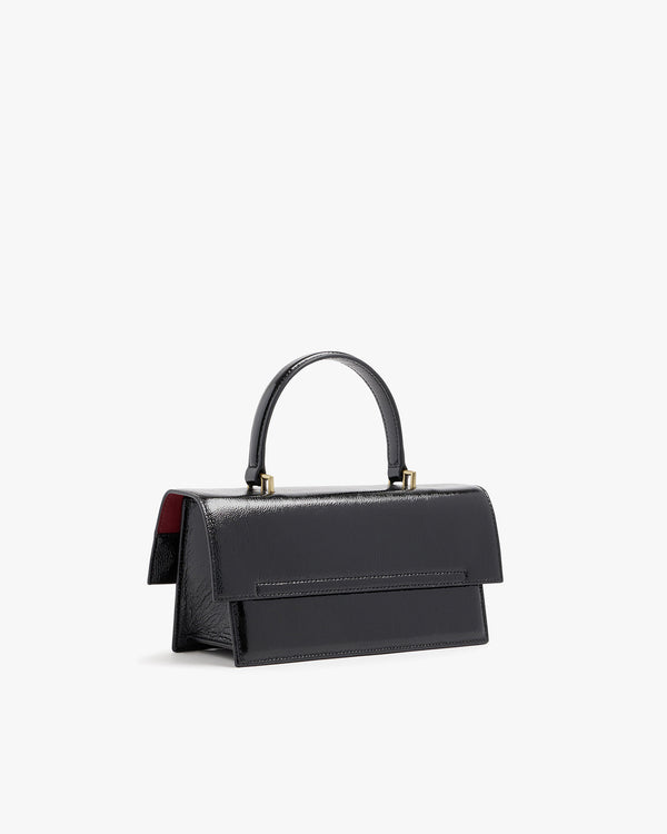THEA bag in black naplak, back three-quarter view, rigid handle, red lining visible under the flap