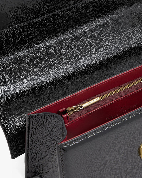 THEA bag in black naplak, close-up of interior with zip pocket, burgundy lining and gold hardware