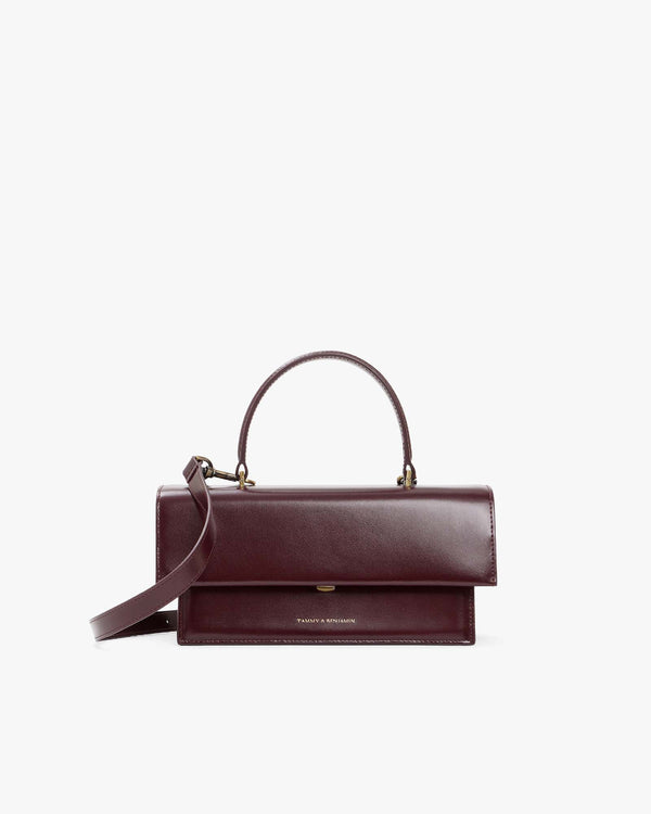THEA bag in Mahogany, front view, flap closed, with top handle and detachable strap