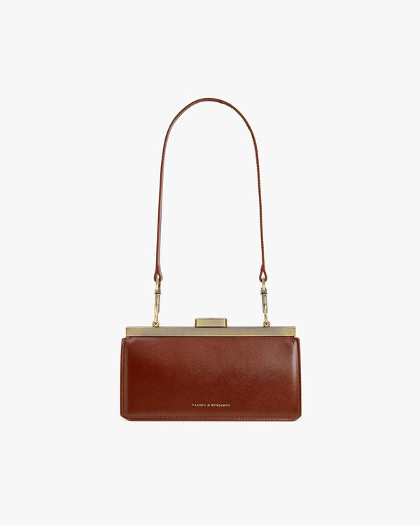 JEANNE BAGUETTE bag in brown, front view, worn on the shoulder with long strap, gold clasp closed