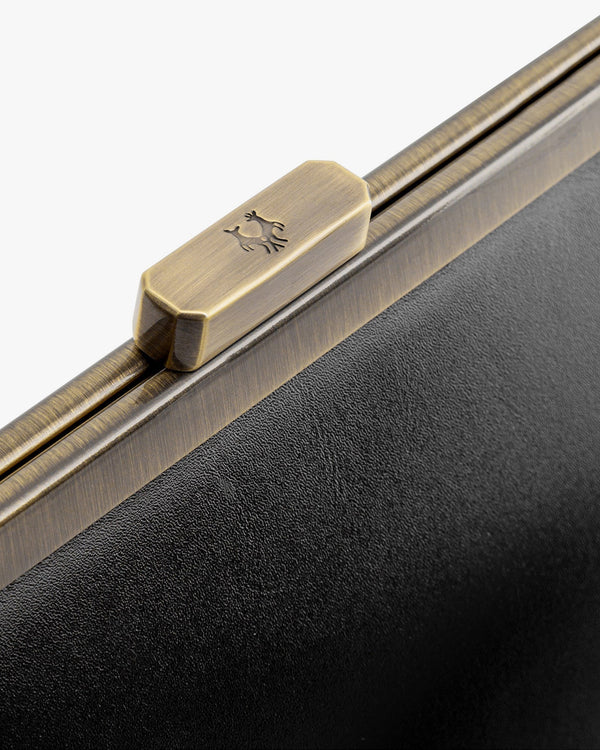 JEANNE BAGUETTE bag in black, close-up on the engraved retro clasp and grained leather