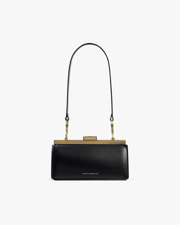 JEANNE BAGUETTE bag in black, front view, worn on the shoulder with gold retro clasp