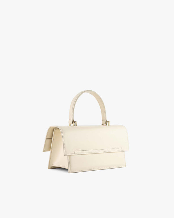 THEA bag in Ivoire, rear three-quarter view, closed flap, rigid handle and gold hardware